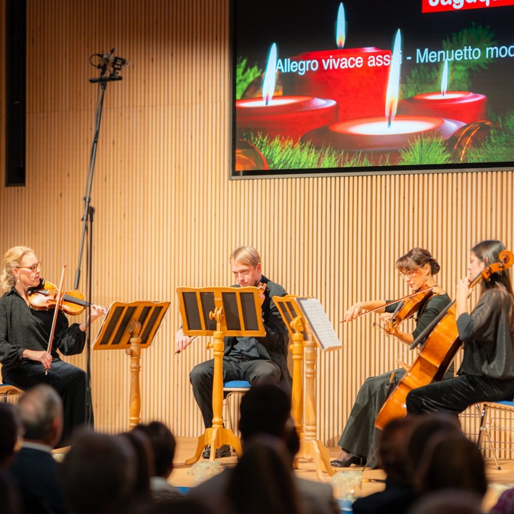 Streichquartett auf der Bühne mit professioneller Mikrofonierung für Audioaufzeichnung. Im Hintergrund ein Teil der LED-Wall mit adventlicher Videoeinspielung